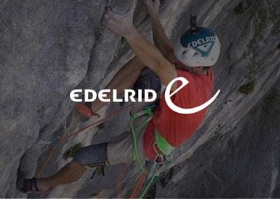 Ein Kletterer an einer steilen Felswand mit EDELRID-Ausrüstung, unterstützt durch FUEGOS TRAGESYSTEME für maximale Sicherheit.